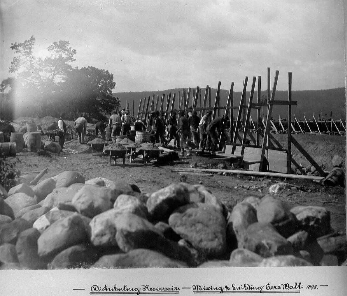 Men mixing concrete and building wall